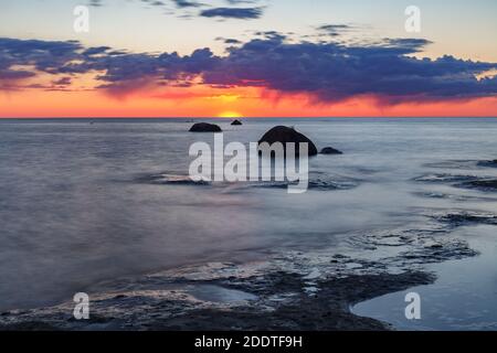 Schöner, farbenfroher Sonnenuntergang über Meer und Felsen. Ostsee. Estland. Langzeitbelichtung. Stockfoto