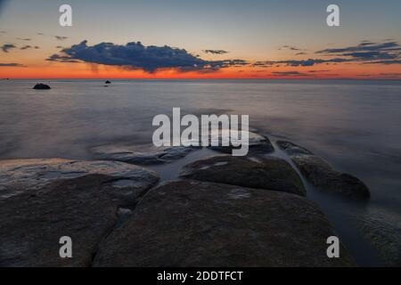 Schöner, farbenfroher Sonnenuntergang über Meer und Felsen. Ostsee. Estland. Langzeitbelichtung. Stockfoto