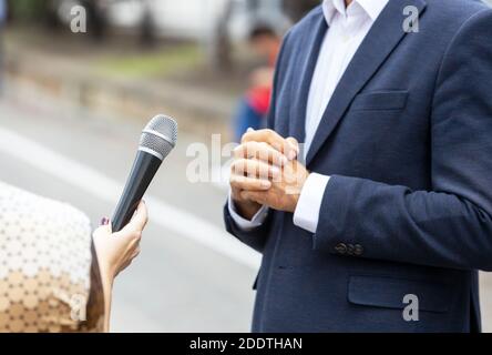 Reporter, der ein Presseinterview mit einer nicht erkennbaren Person macht. Vox populi Konzept. Stockfoto