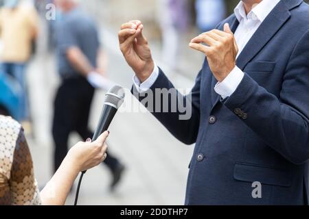 Reporter, der ein Presseinterview mit einer nicht erkennbaren Person macht. Vox populi Konzept. Stockfoto