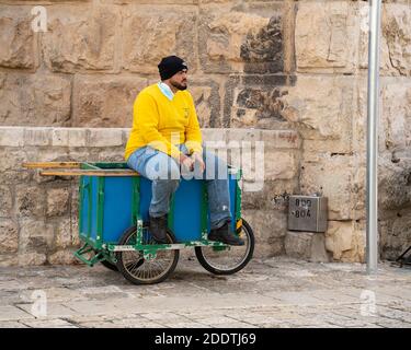 Jerusalem, Israel - 21. November 2020: Ein Portier sitzt auf seinem Wagen, wartet auf Geschäfte, an den Mauern des alten Jerusalem, Israel Stockfoto