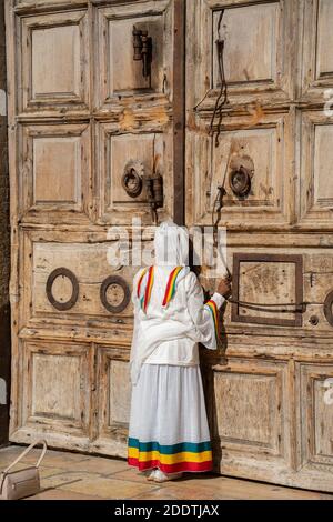 Jerusalem, Israel - 21. November 2020: Eine Frau küsst die verschlossenen Türen der Kirche des heiligen Grabes, Jerusalem, Israel. Stockfoto