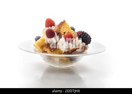 Panettone in Stücken mit Sahne, Erdbeeren, Himbeeren, Brombeeren und Rosinen. Italienisches Dessert für Weihnachten auf dem Teller auf weißem Hintergrund Stockfoto