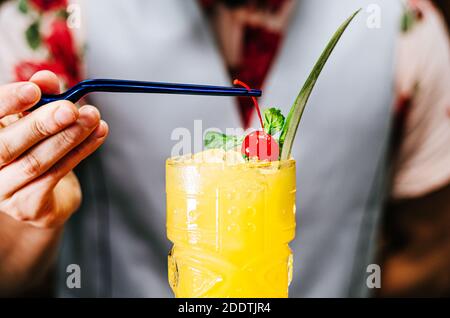 Der Barkeeper bringt eine Kirsche auf einen Tiki-Cocktail Stockfoto