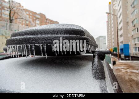 Der schwarze Kofferraum auf dem Dach des Wagens ist im Winter in der Stadt stark vereist und mit Eis bedeckt. Stockfoto