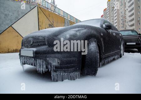 Der schwarze SUV ist eingefroren. Bedeckt mit einer Eiskruste nach dem Regen im Winter. Stockfoto