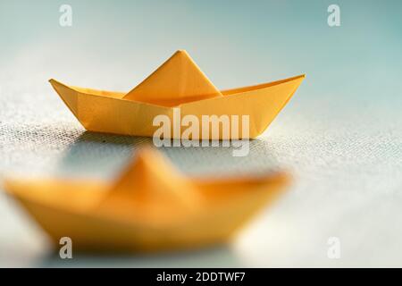 Origami gelbes Segelboot auf einem Meer mit blauem Papier. Papierkunst-Stil Hintergrund mit Schiff und Meer Stockfoto