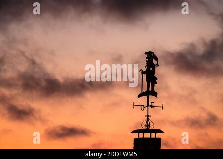 Windfahne in der Form eines Rohrmanns, silhouettiert gegen einen Sonnenuntergang Himmel. Stockfoto