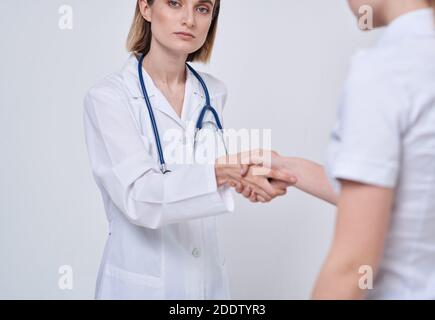 Professionelle Ärztin Frau schüttelt die Hand einer Patientin an Ein heller Hintergrund Stockfoto