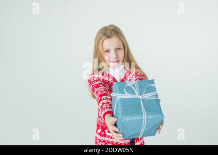 Nettes Mädchen mit Weihnachtsgeschenk.Cute Kind, Kind trägt rot gestrickt Nordic Pullover Holding Geschenk, Box feiert. Happy 2021 Neujahr. Frohe Weihnachten Stockfoto