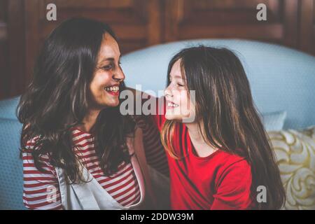 Portrait von Mutter und Tochter lachen und sitzen zusammen Auf dem Sofa - Digitales Porträt der Familie Stockfoto