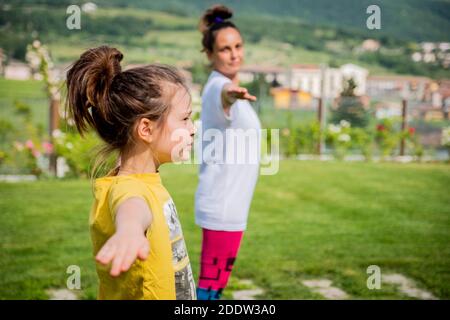 Mutter und Tochter machen Yoga-Übungen im Freien - junge Frau Doing Fitness-Übungen im Park - erreichen Harmonie Stockfoto