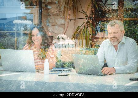 Mann und Frau lachen und arbeiten mit ihrem Laptop zu Hause - Mutter und Vater sind glücklich und arbeiten von zu Hause aus - Selbstisolation Stockfoto