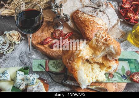 Ein Glas trockener Rotwein und italienisches Focaccia-Brot mit Käse, Olivenöl und getrockneten Tomaten. Traditionelles italienisches gesundes Essen. Selektiver Fokus. Stockfoto