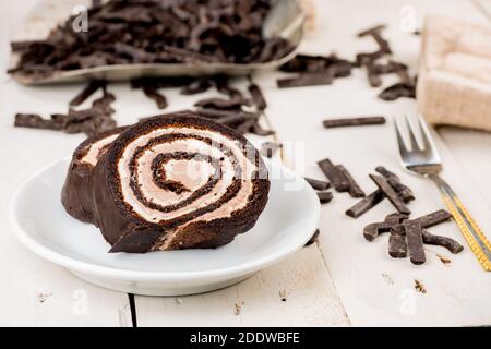 Schweizer Schokoladenkuchen. Samtroulade ohne Mehl Rezept. Glutenfreies hausgemachtes Produkt. Butter Sahne innen. Auf weißem Holztisch. Stockfoto