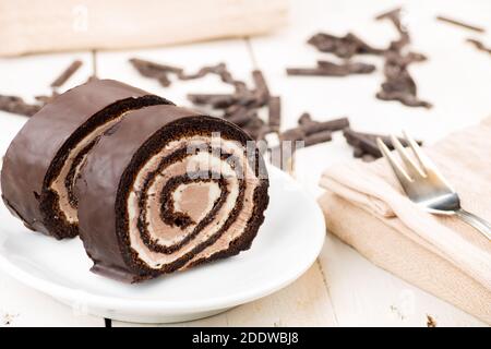 Schweizer Schokoladenkuchen. Samtroulade ohne Mehl Rezept. Glutenfreies hausgemachtes Produkt. Butter Sahne innen. Auf weißem Holztisch. Stockfoto