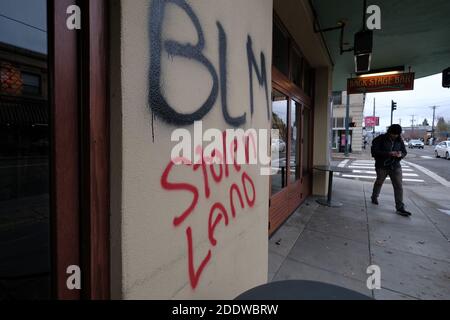 Portland, USA. November 2020. Ein Mann geht am 26. November 2020 am Hawthorne Theater in Portland, Oregon, vorbei an Graffiti aus dem 'Stolen Land', nach einem Aufruf zum Handeln am Thanksgiving-Abend, der indigene Demonstranten dazu aufforderte, Symbole des Kolonialismus, des Kapitalismus und der Gentrifizierung anzugreifen. (Foto: Alex Milan Tracy/Sipa USA) Quelle: SIPA USA/Alamy Live News Stockfoto