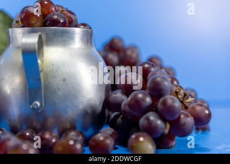 Frische Traubenfrüchte und Beeren. Blauer Hintergrund . Zutat für Säfte und Wein. Traubenbeeren in Aluminium. Stockfoto