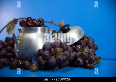 Frische Traubenfrüchte und Beeren. Blauer Hintergrund . Zutat für Säfte und Wein. Traubenbeeren in Aluminium. Stockfoto