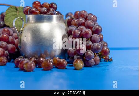 Traubenfrüchte. Zutat für Säfte und Wein. Traubenbeeren in Aluminiumbehälter. Blauer Hintergrund. Menschliche Nahrung Stockfoto
