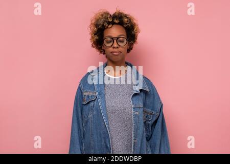 Ruhige hübsche afroamerikanische junge Frau mit geschlossenen Augen an rosa Wand. Stockfoto