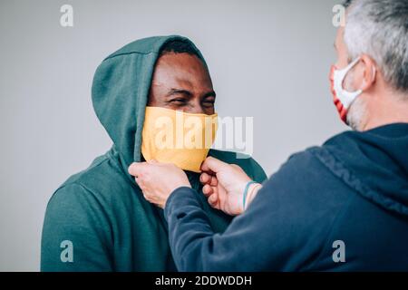 Personal Trainer hilft dem athletischen Mann auf die setzen Schutzmaske vor dem Training in der Pandemieperiode des Kovid19 Stockfoto