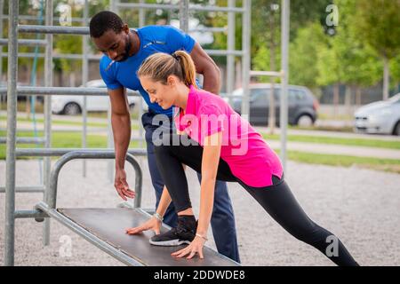 Afro american Fitness-Trainer Coaching helfen Frau tun Liegestütze auf Cross fit horizontale Bar-Station im Park - Young Fitness-Trainer hilft b Stockfoto