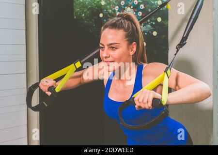 Schönes Mädchen Training ihre Arme mit Trägern TRX Fitness in Die Turnhalle - Frau macht Liegestütze trainiert den Oberkörper Brustschultern Brusttrizeps Stockfoto