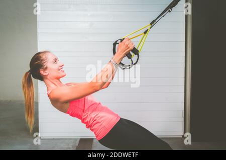 Schönes Mädchen Training ihre Arme mit Trägern TRX Fitness in Die Turnhalle - Frau macht Liegestütze trainiert den Oberkörper Brustschultern Brusttrizeps Stockfoto