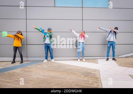 Multiethnische junge Menschen tanzen den DAB Tanz im Freien halten sozial Distanz während der Zeit des Coronavirus - spielerische Schüler Lustige Po Stockfoto