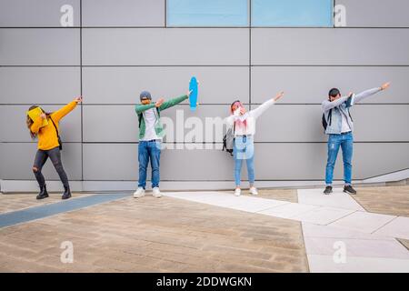 Multiethnische junge Menschen tanzen den DAB Tanz im Freien halten sozial Distanz während der Zeit des Coronavirus - spielerische Schüler Lustige Po Stockfoto