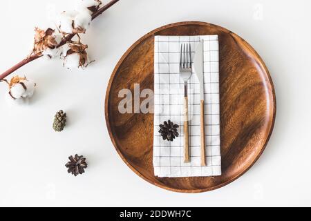 Feminine Hochzeit, Geburtstag Desktop-Mock-up-Szene. Holzschale, Besteck mit karierter Serviette, Baumwollblumen. Weißer Tabellenhintergrund. Flach liegend, oben Stockfoto
