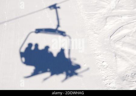 Schatten auf der Skipiste vom Sessellaufzug mit Skifahrern und Snowboardern. Das Problem der Eröffnung eines Skigebiets in der COVID-19 Pandemie. Hochwertige Fotos Stockfoto