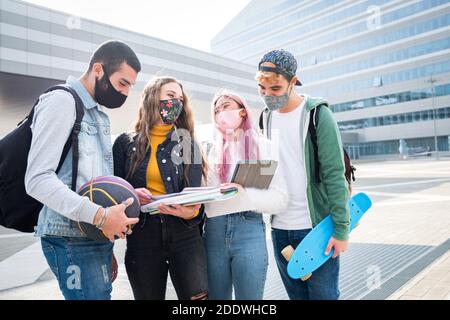 Multirassische Studenten mit Gesichtsmaske studieren am College-Campus - Neues normales Lifestyle-Konzept mit jungen Schülern, die gemeinsam Spaß haben Im Freien Stockfoto