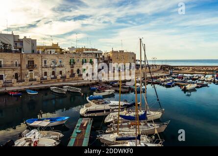 Kleiner Hafen in Giovinazzo in der Nähe von Bari mit bunten Fischerbooten. Befestigte Altstadt direkt am Meer.Apulien/Apulien Südostitalien. Stockfoto