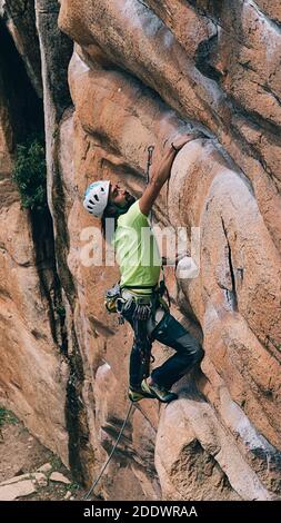 Bärtiger Mann mit Helm und Gurt beim Klettern. Stockfoto