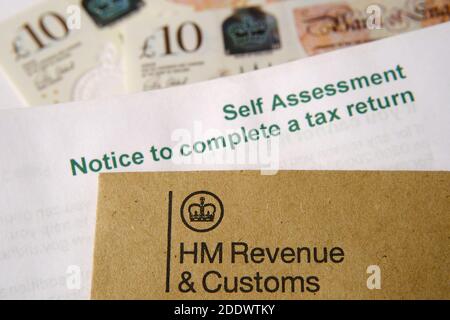 HM Revenue and Customs (HMRC) Buchstaben mit Logos mit dem braunen Umschlag und verschwommenem Selbstbewertungs- und Steuererklärung. Stockfoto