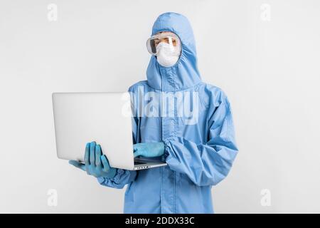 Arzt in Schutzanzug, Maske, Brille und Handschuhe arbeiten mit Laptop, geben Patienten Beratung über Online-Service, auf isoliertem weißen Hintergrund Stockfoto