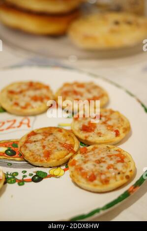 Eine vertikale selektive Fokusaufnahme von kleinen Pizzen auf Eine Platte Stockfoto