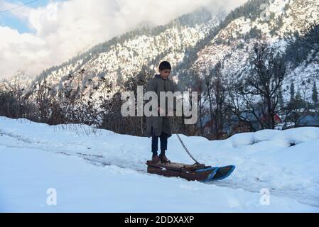 Ganderbal, Indien. November 2020. Ein Baqarwal Junge spielt mit Schneeschlitten außerhalb seines Hauses nach einem Schneefall in Ganderbal Kaschmir.Wetter verbessert sich in Kaschmir Indien nach 3 Tagen, Tag Temperatur steigt, während Nacht Temperatur weiter zu tauchen. Kredit: SOPA Images Limited/Alamy Live Nachrichten Stockfoto