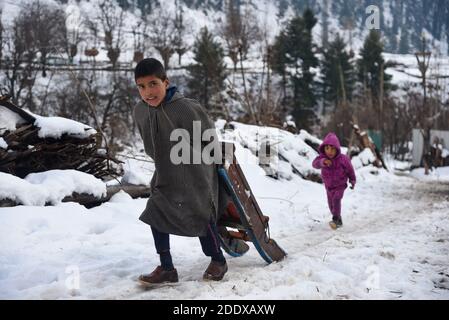 Ganderbal, Indien. November 2020. Ein Baqarwal Junge zieht seinen Schneeschlitten außerhalb seines Hauses nach einem Schneefall in Ganderbal Kaschmir.Wetter verbessert sich in Kaschmir Indien nach 3 Tagen, Tag Temperatur steigt, während Nacht Temperatur weiter zu tauchen. Kredit: SOPA Images Limited/Alamy Live Nachrichten Stockfoto