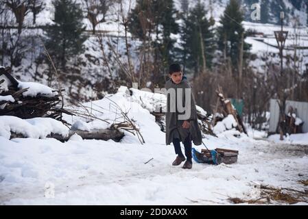 Ganderbal, Indien. November 2020. Ein Baqarwal Junge zieht seinen Schneeschlitten außerhalb seines Hauses nach einem Schneefall in Ganderbal Kaschmir.Wetter verbessert sich in Kaschmir Indien nach 3 Tagen, Tag Temperatur steigt, während Nacht Temperatur weiter zu tauchen. Kredit: SOPA Images Limited/Alamy Live Nachrichten Stockfoto