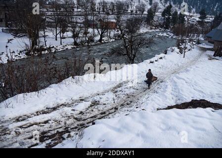 Ganderbal, Indien. November 2020. Ein Baqarwal Junge zieht seinen Schneeschlitten außerhalb seines Hauses nach einem Schneefall in Ganderbal Kaschmir.Wetter verbessert sich in Kaschmir Indien nach 3 Tagen, Tag Temperatur steigt, während Nacht Temperatur weiter zu tauchen. Kredit: SOPA Images Limited/Alamy Live Nachrichten Stockfoto