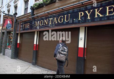 London, Großbritannien. November 2020. Man geht an geschlossenem Montague Pyke Pub auf der Charing Cross RoadEs wurde angekündigt, dass London nach dem Ende der aktuellen Sperre am 2. Dezember in Tier 2 bleiben wird. Ganz England wird wieder in ein Tier-System übergehen, wobei der Großteil des Landes in Tier 2 mit höheren Beschränkungen als zuvor liegt. Weite Gebiete in den Midlands und im Norden werden in Tier 3 gehen, wo zwar nicht unbedingt notwendige Einzelhandelsgeschäfte eröffnet werden können, Pubs und Restaurants jedoch nur noch vor Weihnachten einen Takeaway-Service anbieten können. Kredit: SOPA Images Limited/Alamy Live Nachrichten Stockfoto