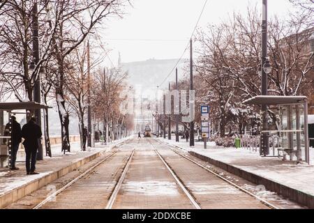 Gelbe Straßenbahn und Schienen auf dem Damm von Buda Seite im Winter mit Schnee in Budapest, Ungarn Stockfoto