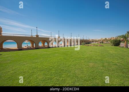 Blick über einen wunderschönen Landschaftsgarten in tropischem Resort mit Große Brücke und Torbögen am Strand Stockfoto