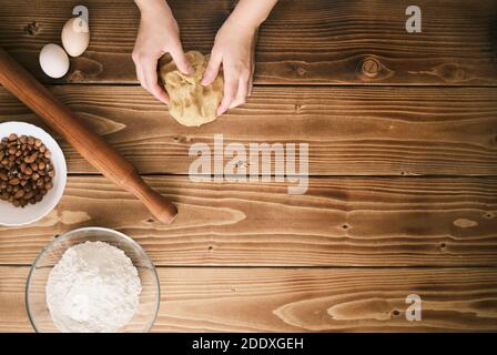 Teig mit weiblichen Händen auf Holztisch machen. Bereit für Text Stockfoto