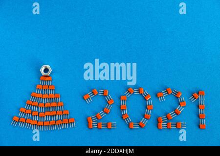 Kreative Weihnachtskarte. Zahlen 2021 und ein Weihnachtsbaum aus Transistoren auf blauem Hintergrund. Kreatives Konzept des neuen Jahres. Speicherplatz kopieren. Stockfoto