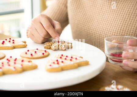 Junge Frau Dekoration hausgemachte Lebkuchen Weihnachtskekse auf weißem Teller In der Küche Stockfoto