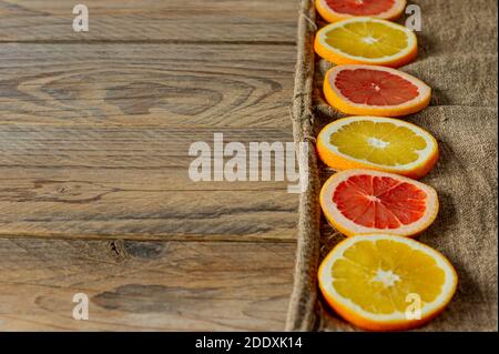 Scheiben von Zitrusfrüchten in einer Reihe. Hintergrund für das Essen. Orangen und Grapefruits auf Eitelrap Stockfoto